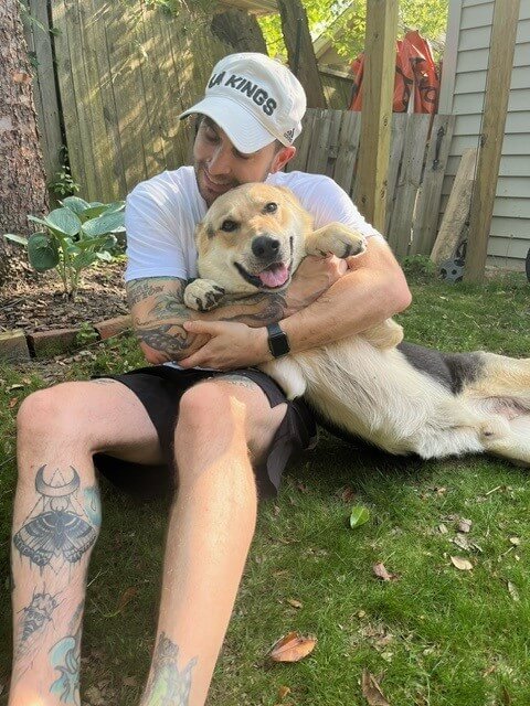 German shepherd mix Timothy gets a hug from his foster guardian.