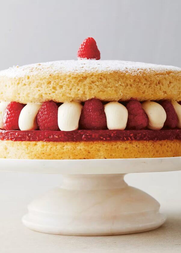 A tiered sponge cake with frosting and raspberries