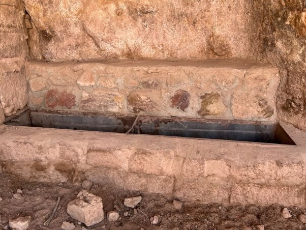 A broken trough set in a rock wall