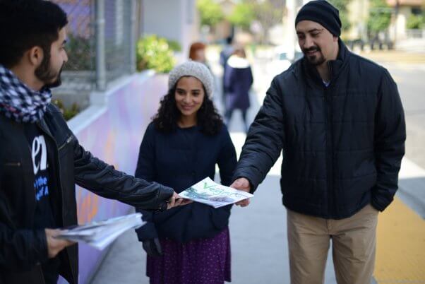 A demonstrator hands out vegan starter guides to passerbys