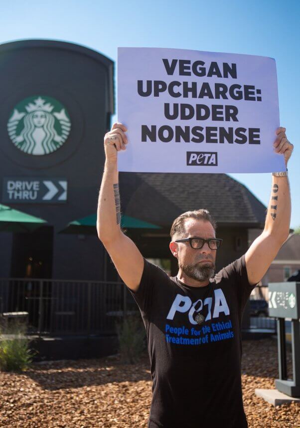 A demonstrator holding a sign in front of a starbucks