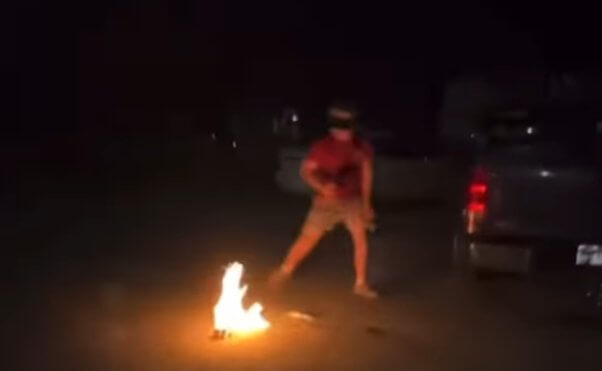 screenshot of a social media video showing a young person backing away from a burst of flames