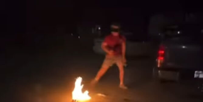 screenshot of a social media video showing a young person backing away from a burst of flames