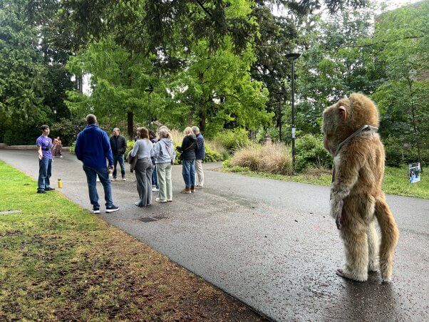 Dorothy mascot stands in front of a group of people on campus