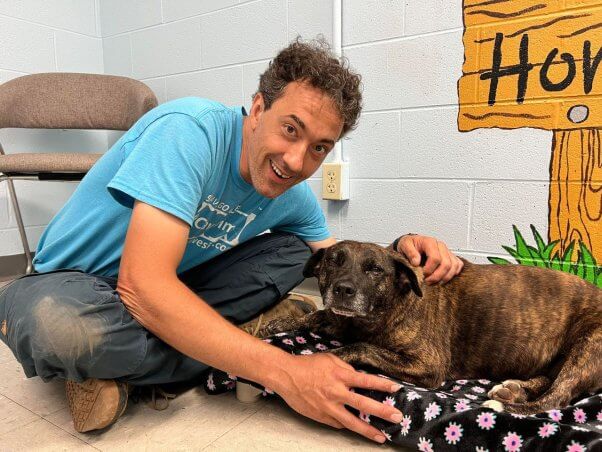 man holds dog laying on a blanket