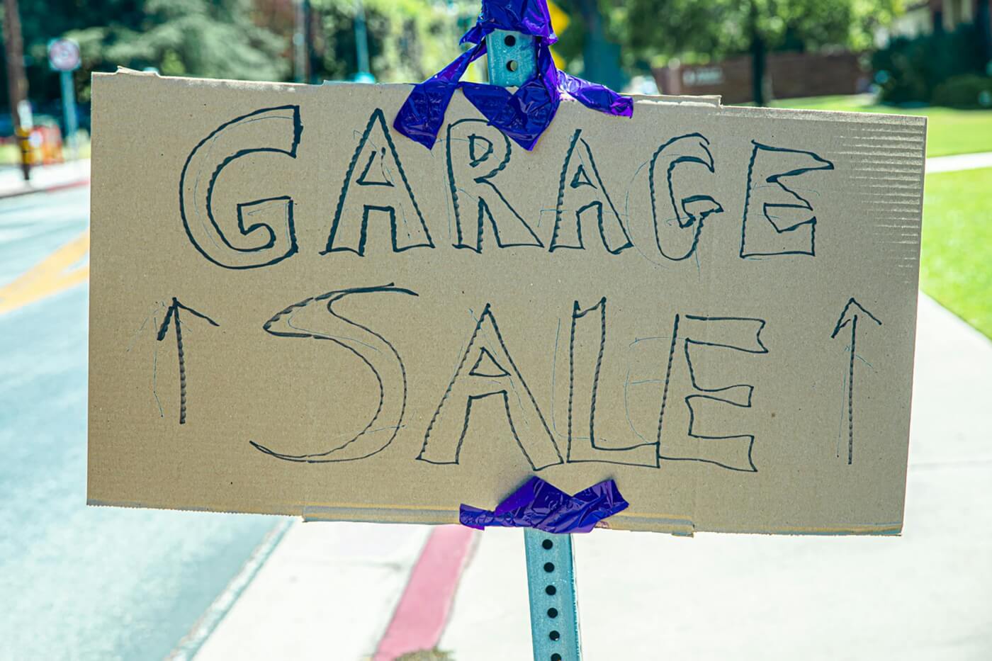 A cardboard sign with writing on it that says garage sale