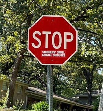 sticker on a stop sign calls attention to Shrine circus animal abuse