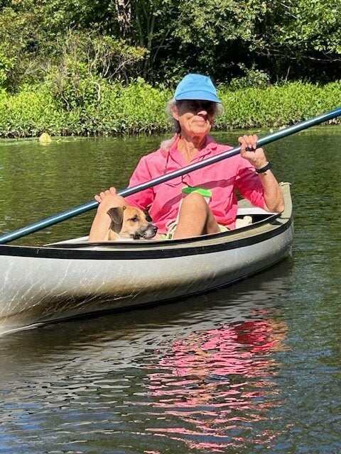 Woman in a canoe with a brown dog