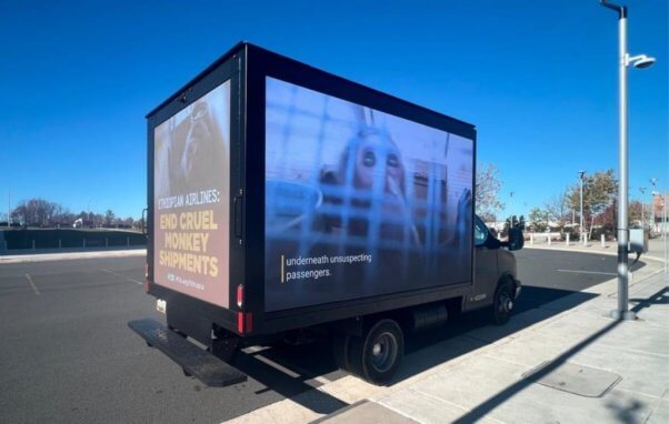 A mobile billboard showing footage of a caged monkey with text reading Ethiopian Airlines: End Cruel Monkey Experiments