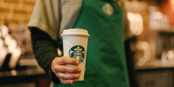 starbucks worker holding cup for warm beverages