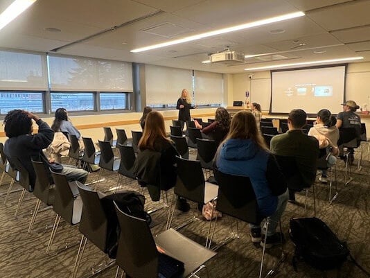 People in a classroom listening to Dr. Lisa