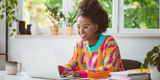 A woman in a colorful sweater at a computer