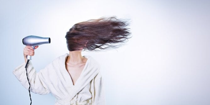 a woman blow dries her hair