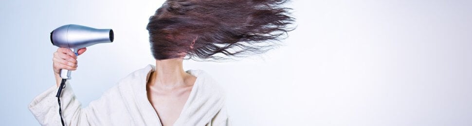 a woman blow dries her hair