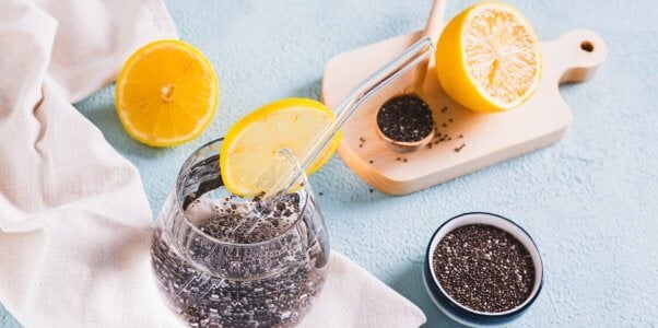 Chia seed water next to bowl of seeds and sliced citrus fruit