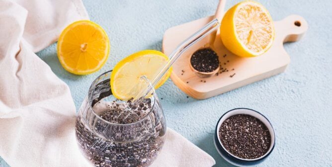 Chia seed water next to bowl of seeds and sliced citrus fruit