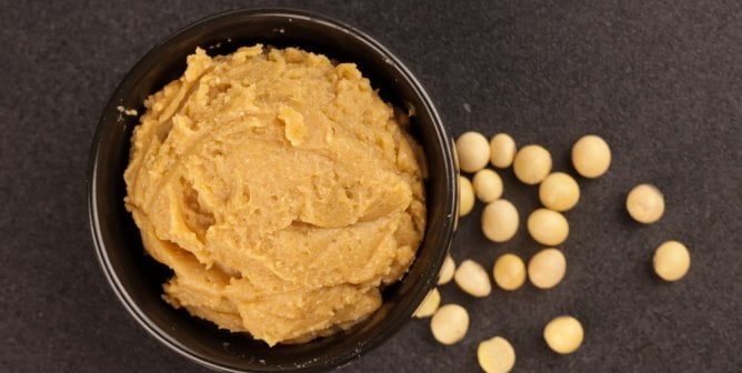 Miso paste in a bowl with scattered chickpeas