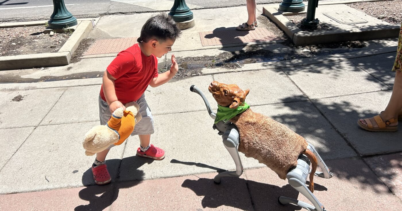 A child high-fiving Charli XC Cow
