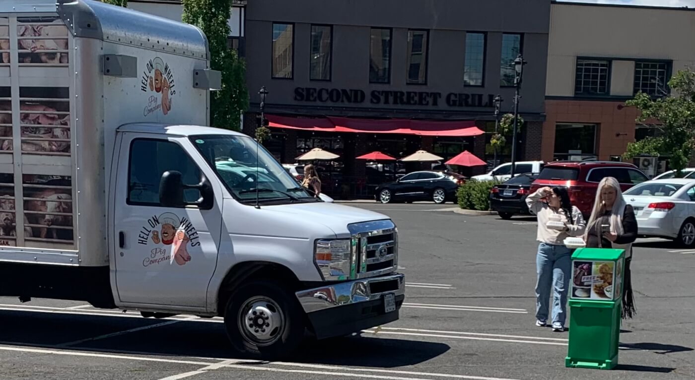 Two bystanders looking at PETA's hell on wheels pig truck