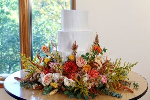 A white wedding cake surrounded by flowers