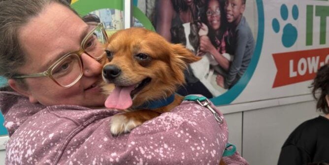 A woman holding a small dog