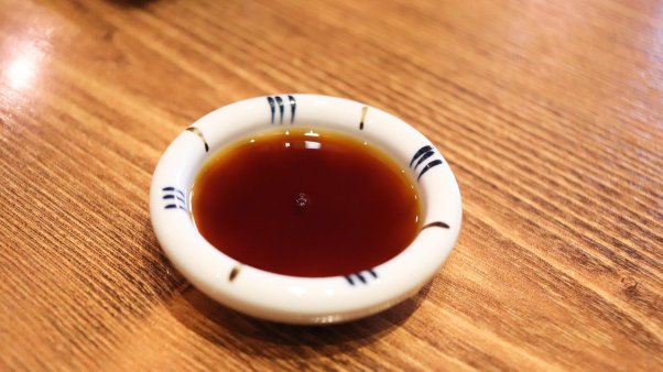 a small bowl of Worcestershire sauce on a wooden table