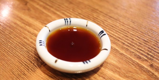 a small bowl of Worcestershire sauce on a wooden table