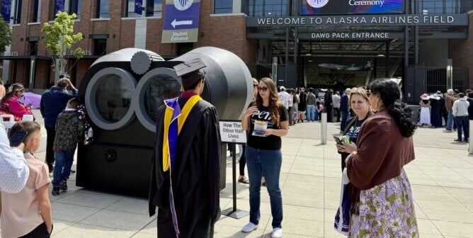 Graduate looks at binoculars display
