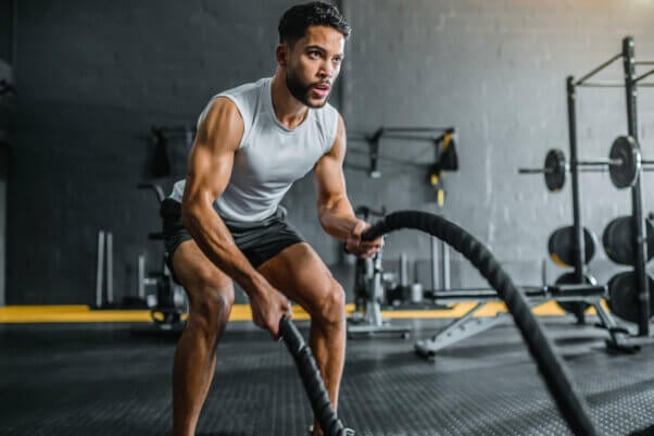 Muscular man working out with battle ropes