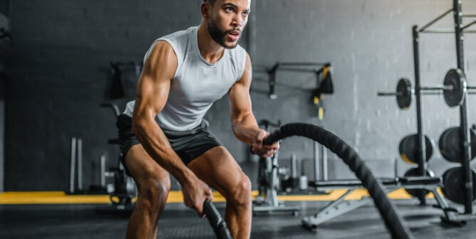 Muscular man working out with battle ropes