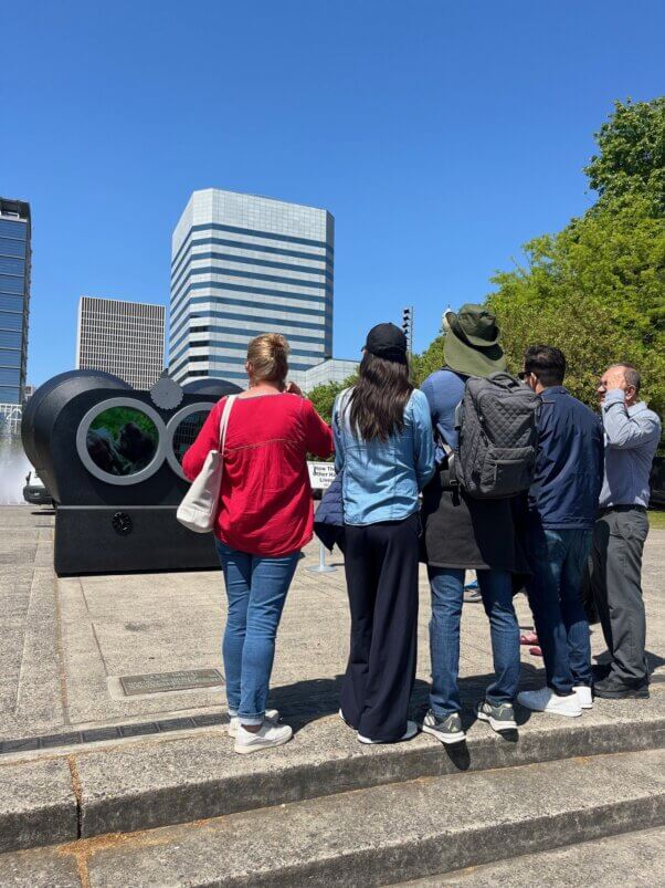 A group of people stands in front of a binoculars model