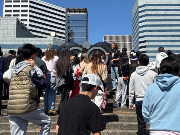Staff member presenting to a crowd in front of the binoculars