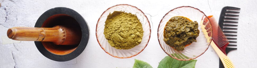 Wooden bowl with rehydrated henna on table .