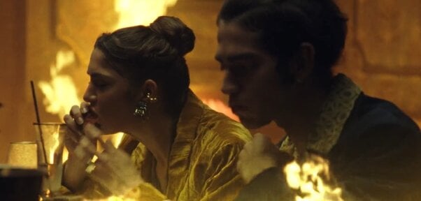 A still from PETA's Room on Fire ad shows two people eating meat in a dining room that is on fire.