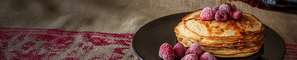 A plate of pancakes covered in raspberries and syrup
