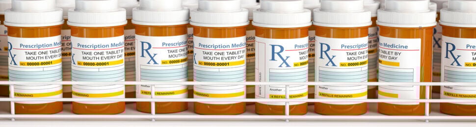 Row of prescription bottles on pharmacy shelf