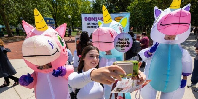 A passerby taking a selfie with PETA's magical unicorns