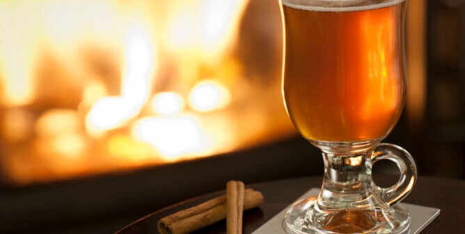 Mulled apple cider and cinnamon sticks in front of fireplace