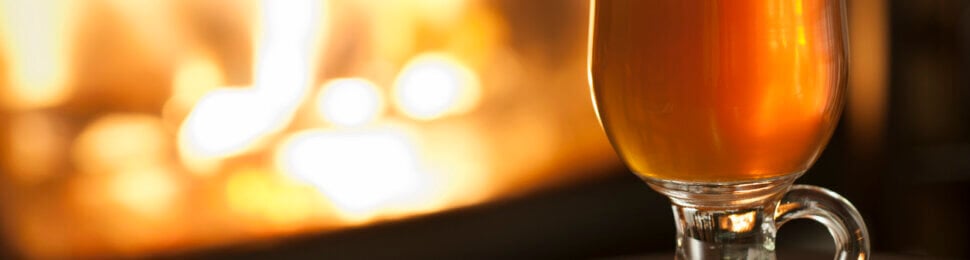 Mulled apple cider and cinnamon sticks in front of fireplace