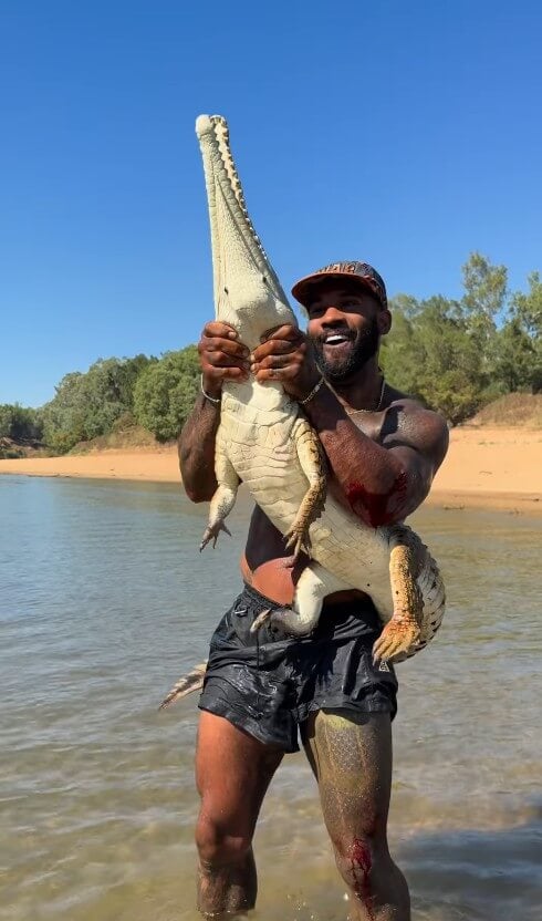 Holston holding up an alligator he had forcibly wrestled to the ground