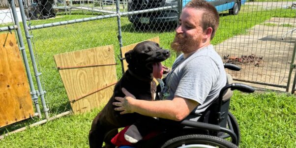 A man holding a black lab dog