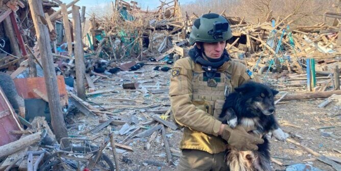 Man holding a rescued dog amidst rubble in Ukraine