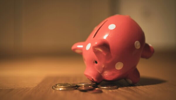 A glass piggy bank 'eating' coins