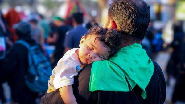 Father carrying child in a crowd