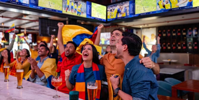 Happy group of friends celebrating a win while watching soccer at a sports bar