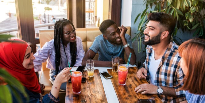 Group of happy friends drinking juice and lemonade at cafe.