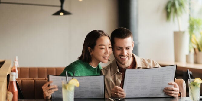 a man and a woman looking at a restaurant menu