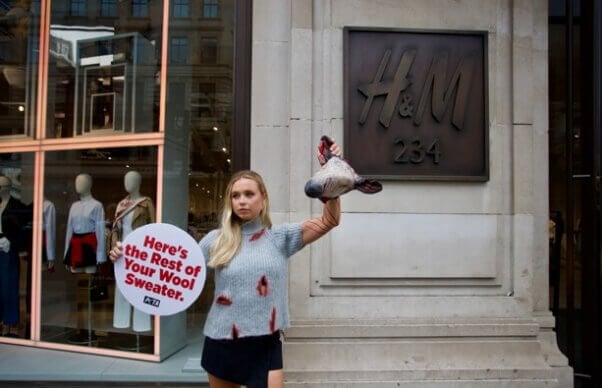 A PETA staff member holds a severed "sheep's head" outside H&M London.