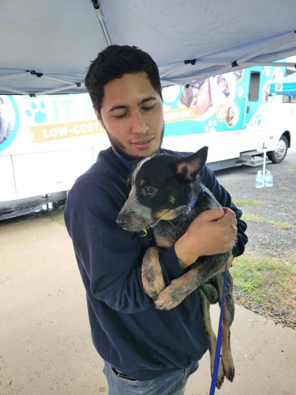 A man holding a dog outside the mobile clinic