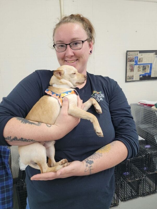 Woman holding little tan dog at PETA clinic in Galax